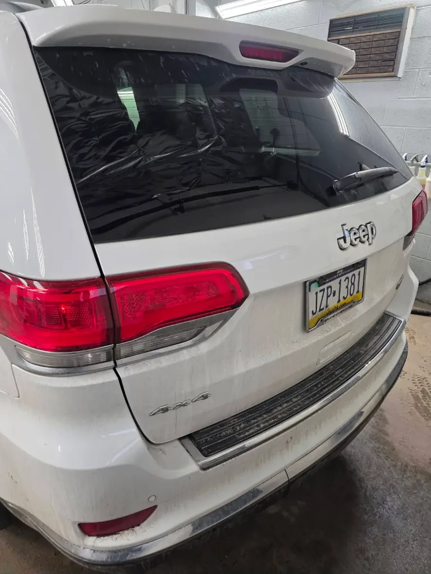 Before: rear of the white Jeep with dirt on the bumper and tailgate